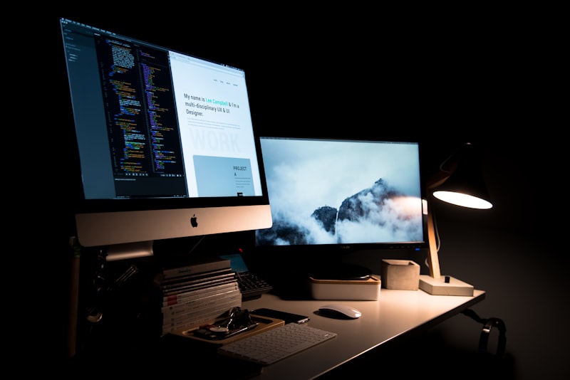 Webdesign-Arbeitsplatz mit Entwurf und Code auf zwei Bildschirmen